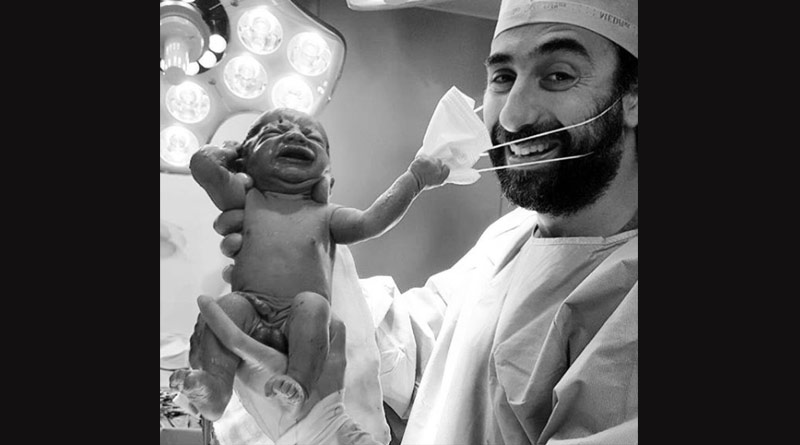 A viral photo of a newborn baby pulling a doctor's surgical mask has become a symbol of hope ।Sangbad Pratidin