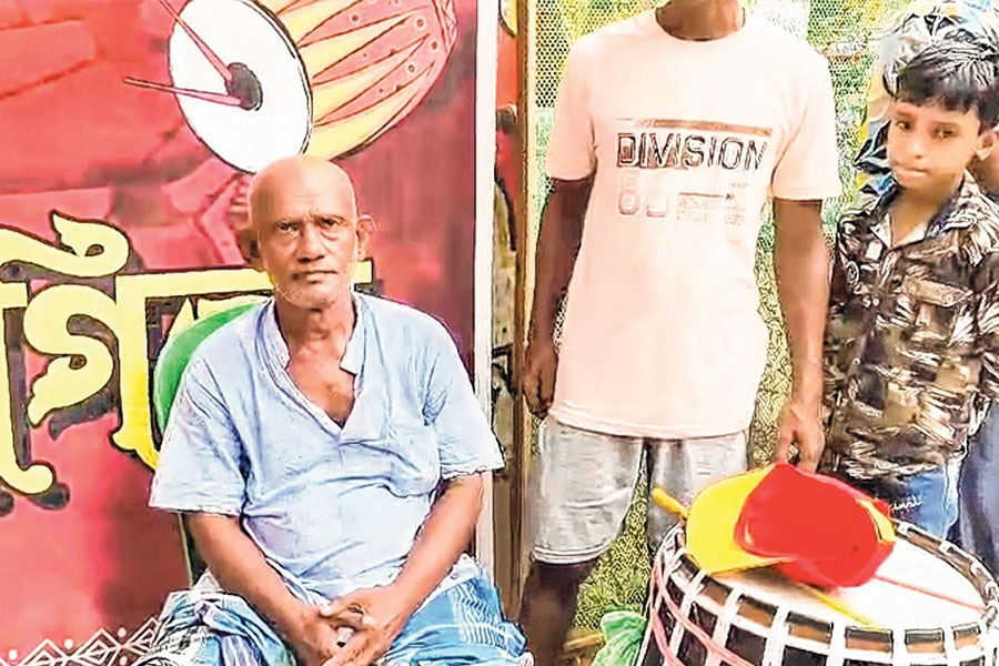 A man plays Dhak while sitting in a wheel chair in Hooghly